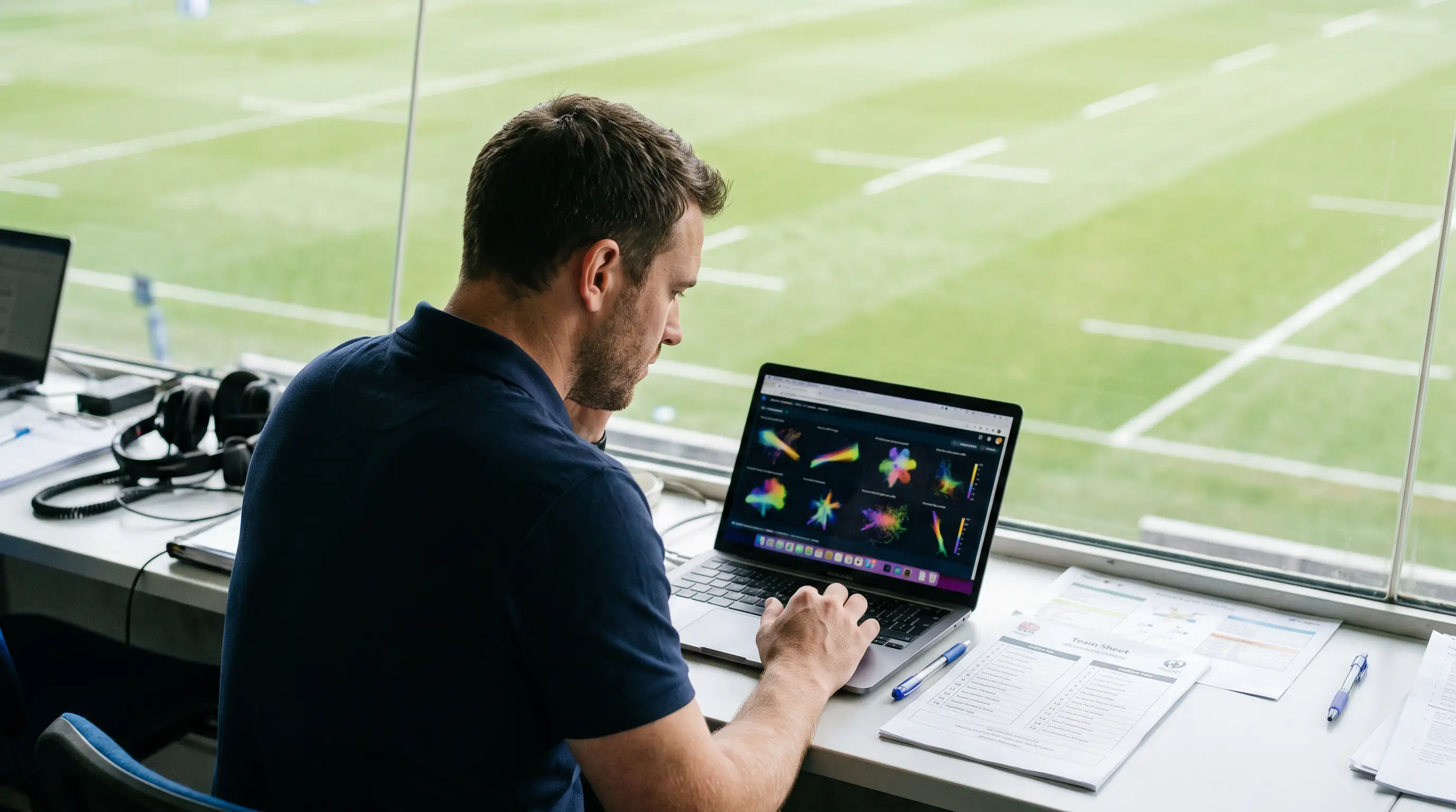Rugby analyst reviewing match statistics on a laptop beside the pitch